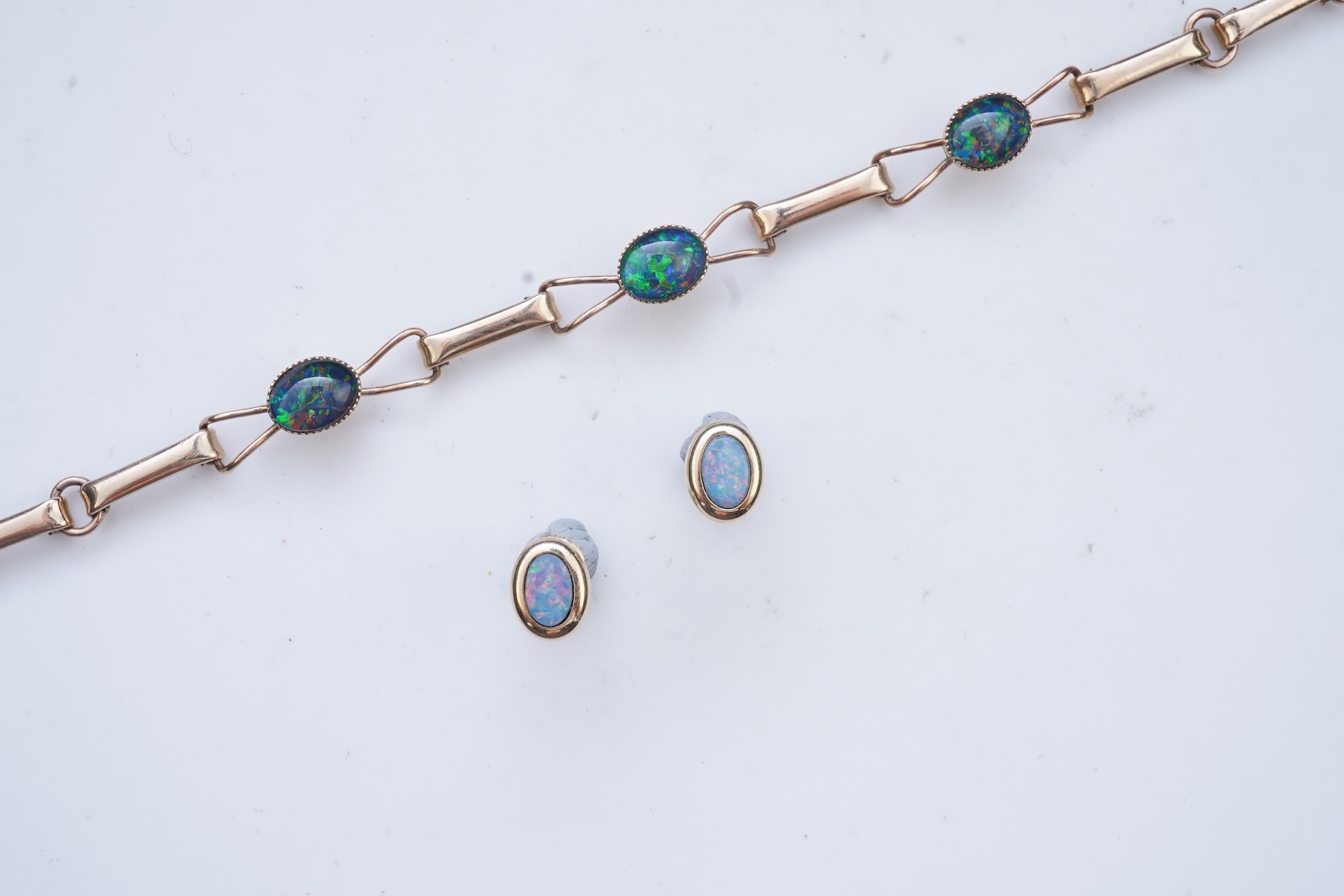 An opal triplet bracelet and pair of earrings, comprising: a gold bracelet set with opal triplets, length 18cm; and a pair of studs set with opal doublets, mounted in gold, length 0.8cm each, post fittings, stamped 585,